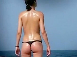 Debout une femme en string fume sur la plage