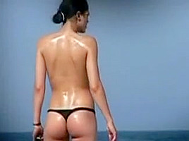 Debout une femme en string fume sur la plage