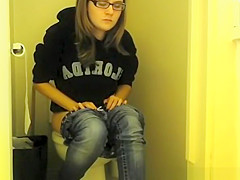 Girl in glasses pees in bathroom toilet
