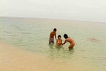 Hot and sexy brunette Asian babe gagging hard cocks and double penetrated on the beach